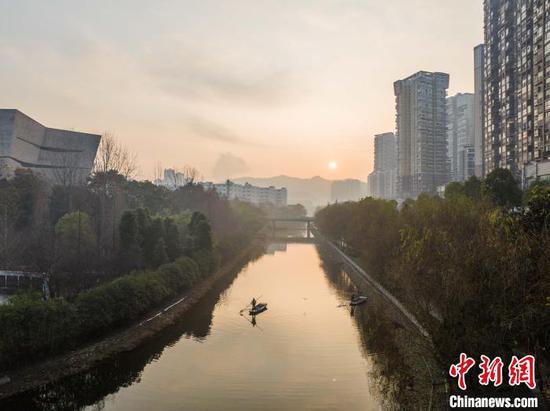1月1日清晨，在毕节市碧阳湖附近的河道里，清洁工人迎着朝阳在水面上进行河道清洁。罗大富 摄