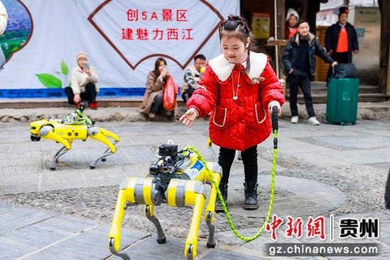 图为小朋友在与智能机器狗互动。