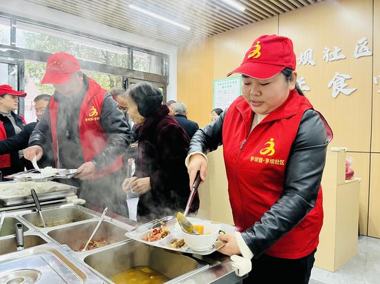 茅坝社区志愿者正在给就餐群众打饭