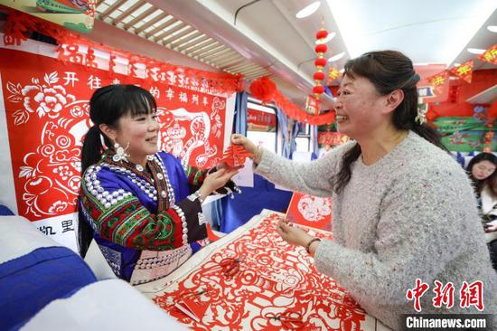 图为旅客在“村火车年货铺”领取“春”字剪纸。中新社记者 瞿宏伦 摄