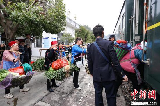 图为村民将农特产品挑上“村火车”售卖。中新社记者 瞿宏伦 摄