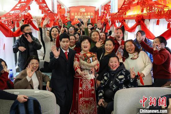 图为在“村火车”上举行金婚纪念的一对夫妻和旅客合影。中新社记者 瞿宏伦 摄