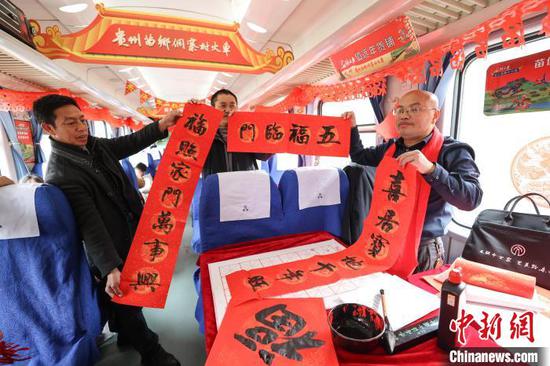 图为旅客展示在“村火车”上领取的春联。中新社记者 瞿宏伦 摄