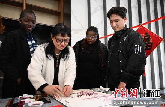 图为:民革浙江省直五支部党员王滢创作年画引人观看。中新社记者 王刚 摄