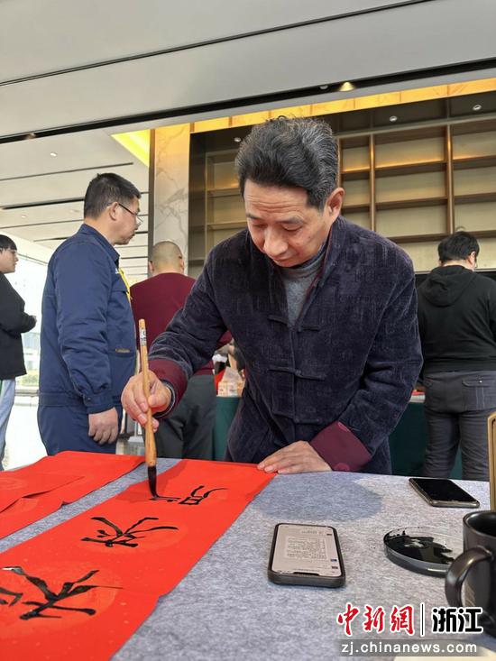 图为:民革浙江省直五支部党员景迪云书写春联。中新社发 陈出新 摄