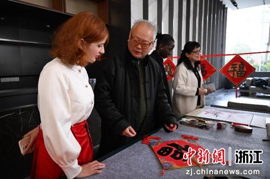 图为:民革浙江省直五支部主委田振玉为国际友人讲解春节送福字的寓意。中新社记者 王刚 摄