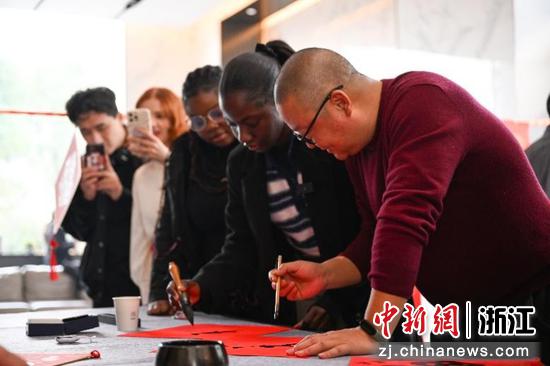 图为:民革浙江省直五支部党员旷雄白现场写福引人观看。中新社记者 王刚 摄