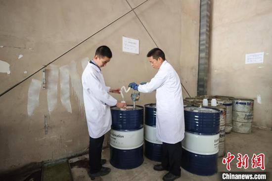 1月24日，贵州省贵阳市，“化验工”杨鸿(左)、高进在提取变压器油料。中新社记者 瞿宏伦 摄