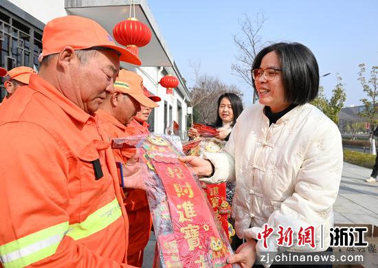 图为:中国新闻社驻浙机构管委会委员张茵(右)在余杭城管驿站赠送年礼。中新社记者 王刚 摄