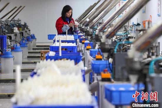 图为工人在查看羽毛球扎线情况。中新社记者 瞿宏伦 摄