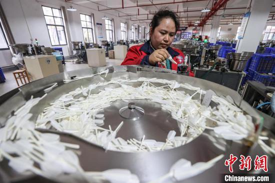 图为工人在查看羽毛球毛片质量。中新社记者 瞿宏伦 摄