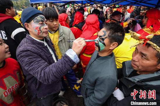 图为活动开始前舞龙者在画花脸。中新社记者 瞿宏伦 摄