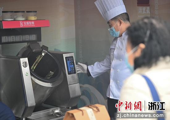 图为:厨师操控自动炒菜机吸引市民。中新社记者 王刚 摄