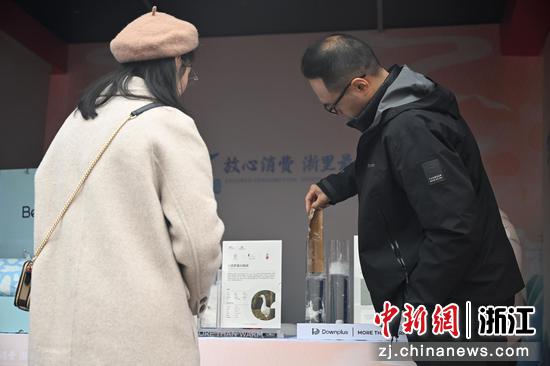 图为:企业代表为市民展示其羽绒产品的防水性能。中新社记者 王刚 摄