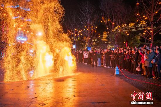 图为游客峰林布依景区观看非遗火壶。 图为游客峰林布依景区观看非遗火壶。