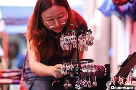 绣里淘非遗集市里的“银饰+苗绣”组合耳饰吸引游客选购。中新社记者 瞿宏伦 摄