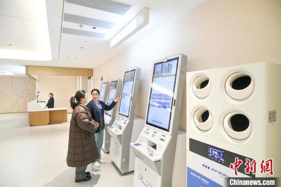 2月26日，天津，医护人员在医院一楼大厅自助服务区指导患者使用自助挂号机。中新社记者 佟郁 摄