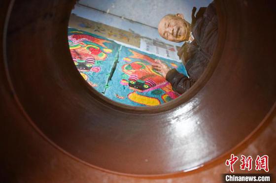 图为王学勤展示“缸鱼年画”在水缸中呈现的倒影。记者 佟郁 摄 图为王学勤展示“缸鱼年画”在水缸中呈现的倒影。记者 佟郁 摄