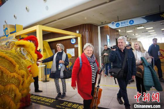 图为国际旅客在天津国际邮轮母港与中国舞狮表演演员互动。中新社记者 佟郁 摄