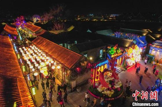 1月25日晚,“杨柳焕新金蛇舞 古韵今章入画来”天津杨柳青古镇迎春主题活动启幕。春节将至,天津杨柳青古镇焕然一新迎接新春佳节的到来。作为天津最具代表性的历史文化古镇之一,杨柳青古镇在保留传统韵味的同时,全面升级街区内的灯光系统,为市民和游客打造了一个充满年味的沉浸式体验。图为市民和游客在杨柳青古镇赏灯游玩。(无人机照片)中新社记者 佟郁 摄