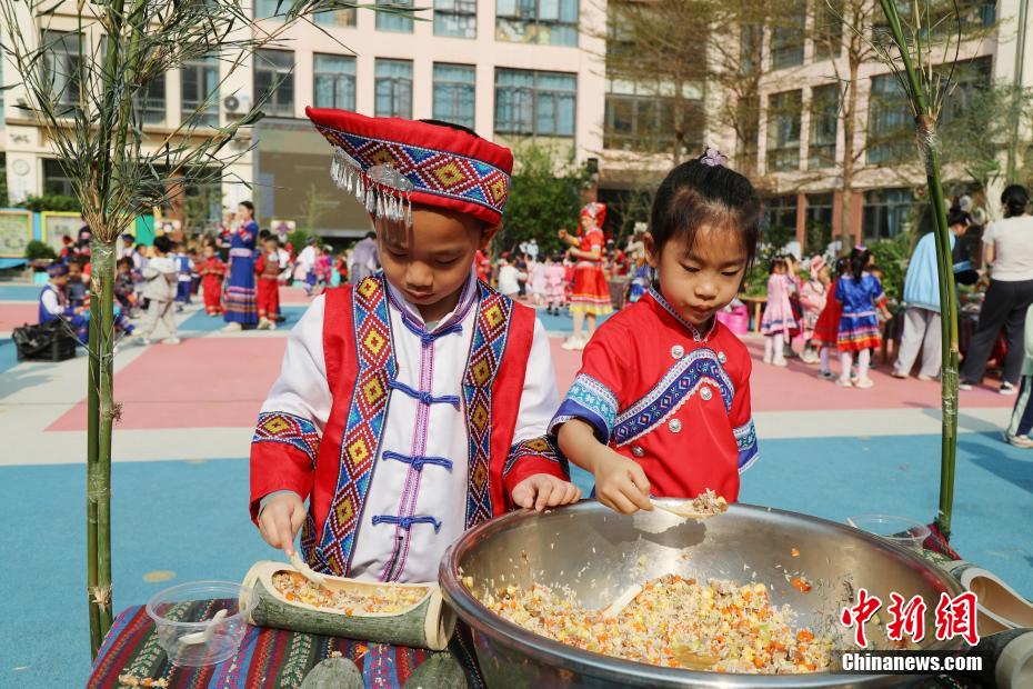 3月27日，在广西南宁市邕宁区一所幼儿园内，师生身着民族服装参加“三月三”民俗活动，通过体验民俗美食一条街、民俗手工一条街的形式，欢度充满童趣与文化气息的“三月三”。图为小朋友在制作竹筒饭。卢虹灵 摄