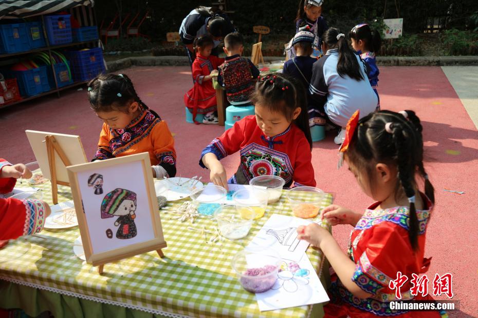 3月27日，在广西南宁市邕宁区一所幼儿园内，师生身着民族服装参加“三月三”民俗活动，通过体验民俗美食一条街、民俗手工一条街的形式，欢度充满童趣与文化气息的“三月三”。图为小朋友在制作“点米成画”。卢虹灵 摄