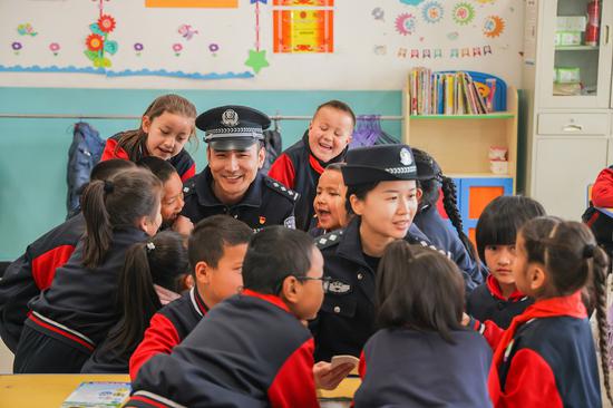 4 月 9 日，哈密公安处民警与花园乡第一小学的学生们围坐在一起，面对面回答学生提问，现场氛围欢快融洽。