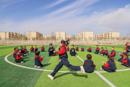 4月9日，哈密公安处民警和花园乡第一小学的学生们在户外开展互动游戏，学生们热情参与。