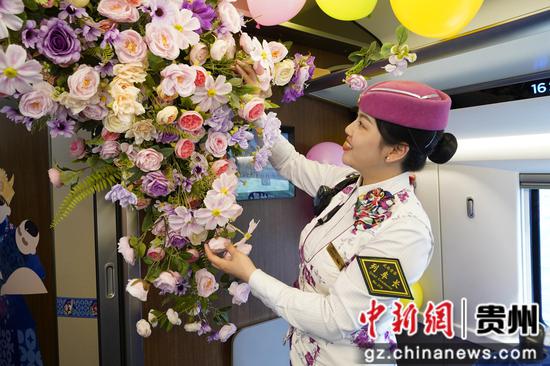 列车长杨婷婷用鲜花布置车厢，欢迎旅客乘车前往百里杜鹃景区赏花。游滨礼 摄
