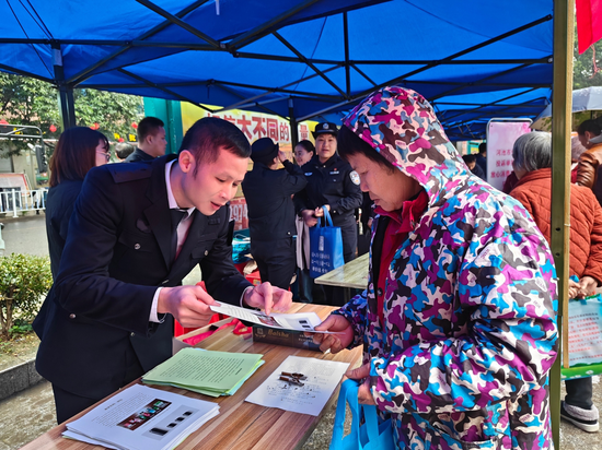 图为执法人员向群众介绍涉烟举报政策。韦子生 摄
