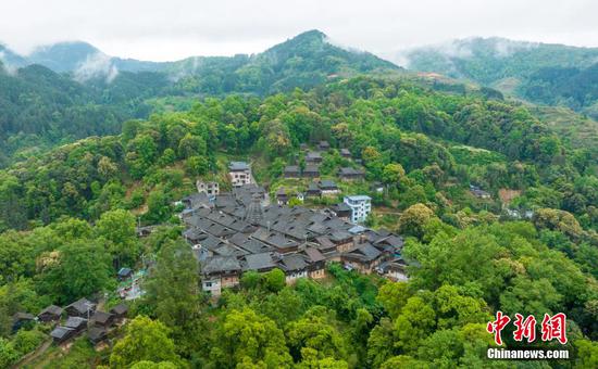 航拍岑报苗寨，错落有致的苗族民居与苍翠的青山交相辉映。