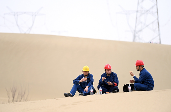 4月27日，新疆送變電公司員工完成巡視后在塔克拉瑪干沙漠中午餐。馬元 攝