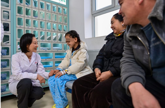 在新疆生产建设兵团第一师医院,吴玲燕(左)鼓励即将做手术的小朋友(2024年12月25日摄)。新华社记者 丁磊 摄