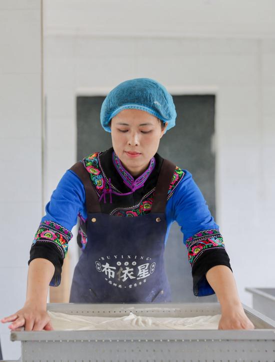 ↑ 4月25日，在作坊内，陈星星用豆腐布将豆腐包裹好。