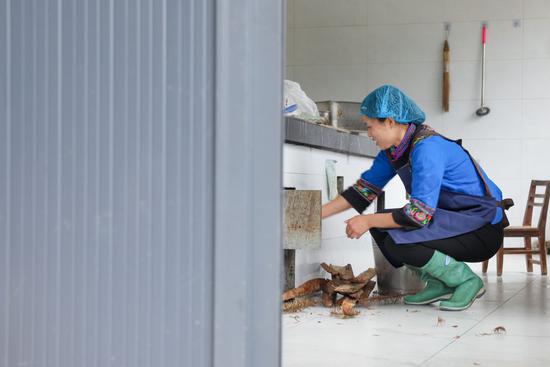 ↑ 4月25日，在作坊内，陈星星添加柴火煮豆浆。