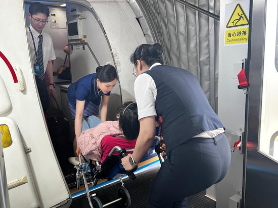 图为南航工作人员用机上轮椅将旅客抬入客舱。吕琳瑜 摄 图为南航工作人员用机上轮椅将旅客抬入客舱。吕琳瑜 摄