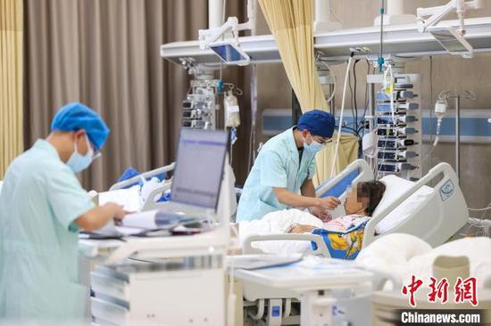 图为李学建(右)在为患者进行基础护理。中新社记者 瞿宏伦 摄