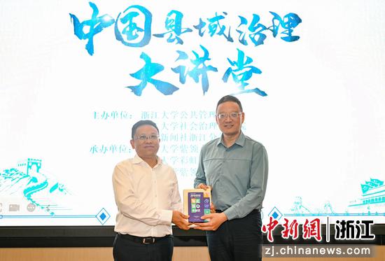 图为:中国新闻社浙江分社副社长严格(右)向中共嵊州市委书记裘建勇(左)赠书。中新社记者 王刚 摄
