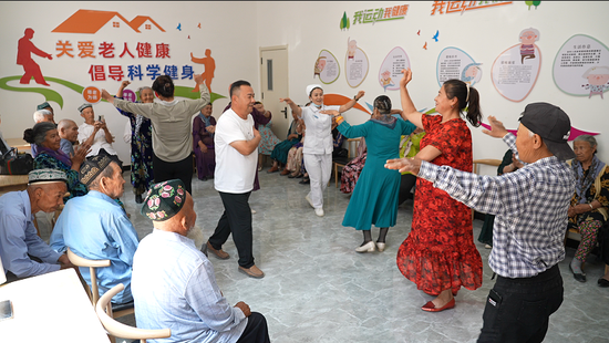 5月14日,艾丁湖镇幸福大院工作人员与老人们共同跳起欢乐的舞蹈。苏银东 摄