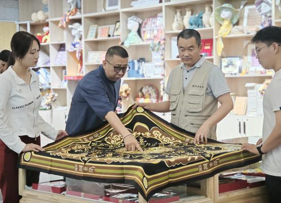 5月18日,若羌县楼兰博物馆馆长冯京(右二)、壹方恒远文化传媒公司的负责人孙虎(左二)在楼兰博物馆文创产品展区讨论刚刚上市的“锦绣楼兰”系列“延年益寿”丝巾。郭城 摄 5月18日,若羌县楼兰博物馆馆长冯京(右二)、壹方恒远文化传媒公司的负责人孙虎(左二)在楼兰博物馆文创产品展区讨论刚刚上市的“锦绣楼兰”系列“延年益寿”丝巾。郭城 摄