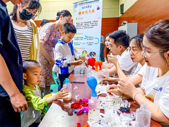  5月17日，中国科学院天津工业生物技术研究所举行了以“生物制造启未来”为主题的公众科学日活动。900余名中小学生及社会公众走进研究所，共同探索生物制造的奥秘。图为少年儿童体验酵母吹气球。记者 佟郁 摄