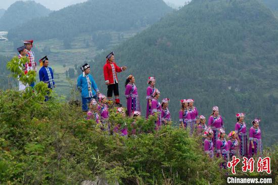 2023年,身穿红色衣服的王波(左五)与村民在山里唱山歌。(受访者供图) 2023年,身穿红色衣服的王波(左五)与村民在山里唱山歌。(受访者供图)