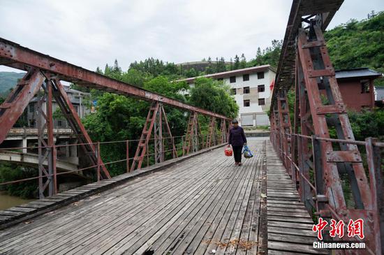 5月23日，一位村民经过重安“三朝桥”钢架桥上。