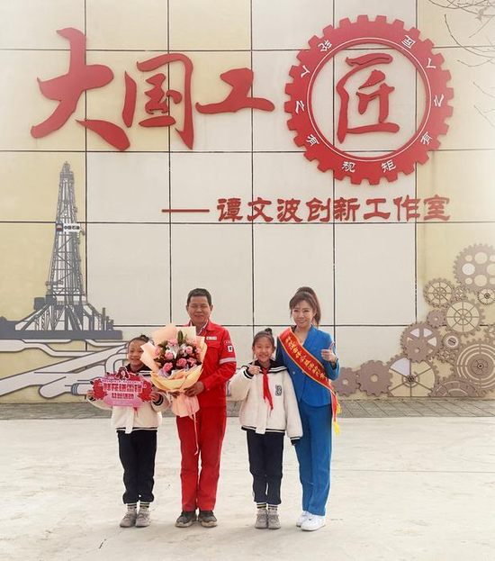 今年3月5日，“鲜花送雷锋”形象大使和市绿雅小学“庄仕华中队”学生代表将鲜花送给“大国工匠”、自治区道德模范谭文波（左二）。克拉玛依融媒记者 非尔代维斯·热夏提 摄