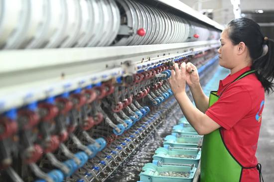 图为民众在现代化纺织绸厂工作。蒋雪林 摄