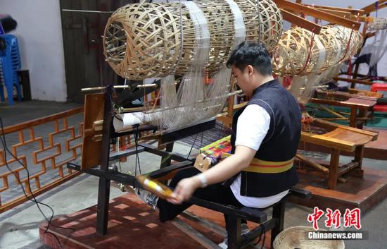 图为当地民众在使用传统织布机织壮锦。忻城县融媒体中心供图