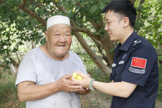 吾甫尔大叔与民警分享丰收的甜蜜果实。苗一家鑫摄