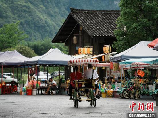 6月15日，游客在贵州省江口县云舍村骑车游玩。中新社记者 周燕玲 摄