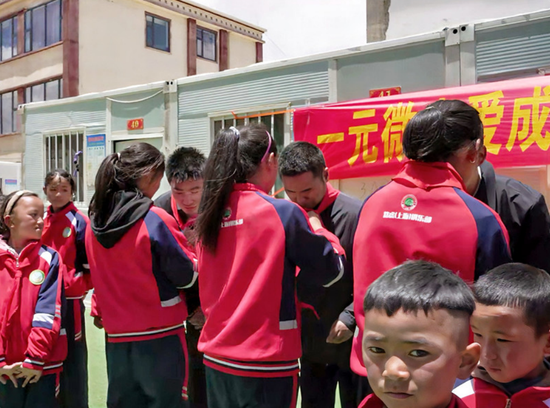 完全小學受助學生為志愿者佩戴紅領(lǐng)巾。旦增 攝