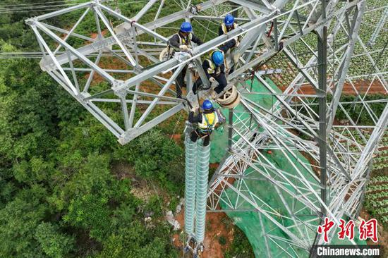 6月18日，工人在安装输电线路绝缘子串。（无人机照片）中新社记者 瞿宏伦 摄